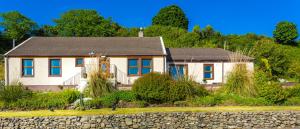 a white house with a gray roof and a stone wall at Cairnryan Bed and Breakfast in Cairnryan