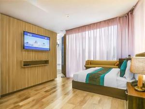 ニューデリーにあるAIRPORT HOTEL Almati EN With Free Airport Pickup Delhi Airportのベッドと薄型テレビのある寝室