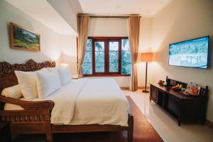 a bedroom with a large bed and a television at Bumi Kinar Heritage in Ubud