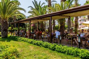 a group of people sitting at tables in a garden at Hotel Aqua in Marmaris