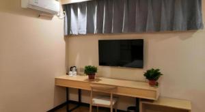 a desk in a room with a television and two plants at Shell Taiyuan South Station Shanxi University Hotel in Taiyuan +20 photos