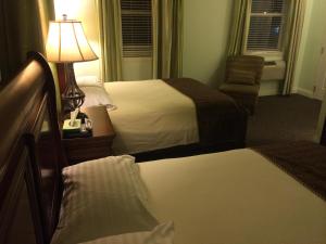 a hotel room with two beds and a lamp and a chair at The City Hotel Bar & Grill in Northern Cambria