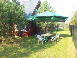 a table and chairs under a green umbrella in a yard at Dom na Mazurach in Spychowo