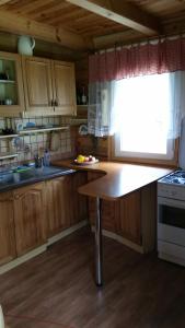 eine Küche mit Holzschränken, einem Tisch und einem Fenster in der Unterkunft Dom na Mazurach in Spychowo