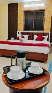 a hotel room with a bed and a tray with two tea cups at Hotel Kiran Palace and Mahi Galaxy in Osiān +6 photos