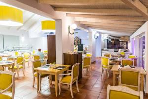 a restaurant with tables and yellow chairs and a kitchen at Keri Village & Spa by Zante Plaza (Adults Only) in Keri