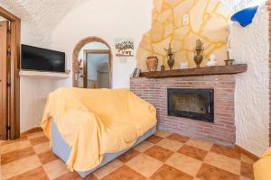 a living room with a fireplace and a yellow blanket at La Higuera in Benalúa de Guadix