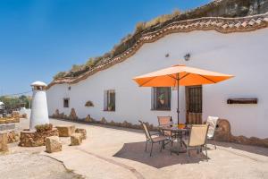 a table and chairs with an umbrella in front of a building at La Higuera in Benalúa de Guadix