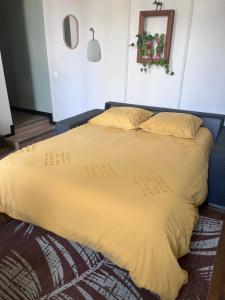 a large bed with a yellow comforter and pillows at Appartement Hedas hyper centre in Pau +1 photo