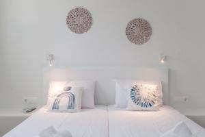 Un dormitorio con una cama blanca con dos almohadas. en A Tinian Room 1, en Tinos 16 fotos más