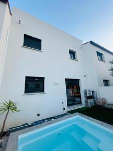 a swimming pool in front of a white building at Belle chambre dans villa neuve avec piscine in Perpignan