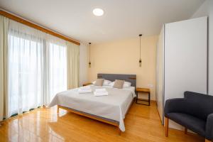 a bedroom with a large bed and a chair at Boutique rooms Kican in Metković
