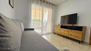 Una sala de estar con un sofá y un televisor de pantalla plana. en Cozy apartment beach 300 metros, en Santa Pola