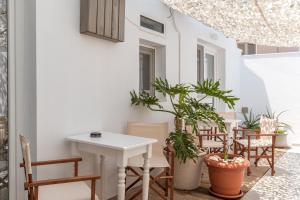 un patio con una mesa blanca, sillas y plantas en A Tinian Room 4, en Tinos 15 fotos más