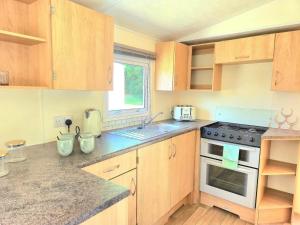 a kitchen with wooden cabinets and a stove top oven at Cherry, 2 Bed, 6 Berth With Electric Panel Heaters 70724C in Great Yarmouth