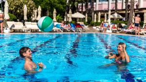 two children playing in a swimming pool with a beach ball at Hotel Aqua in Marmaris