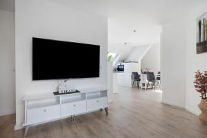 a white living room with a flat screen tv on a wall at Ferienwohnung 1 in Bad Salzuflen