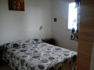 a bedroom with a bed with a black and white comforter at Cabañas Del Sol in Las Compuertas