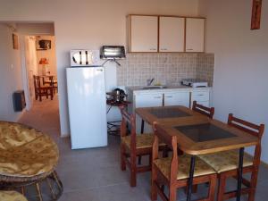 a kitchen with a table and a white refrigerator at Cabañas Del Sol in Las Compuertas