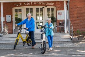 an older man and woman with their bikes outside a building at Hotel Alte Fischereischule in Eckernförde