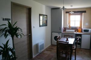 a kitchen with a table and chairs and a table and a door at La Grange de Noëlie in Lanuéjouls