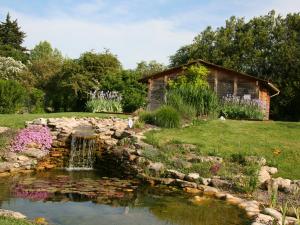 a pond in a garden with a stone wall at Couleur Lavande in Le Thor