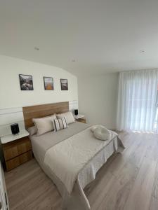 Un dormitorio blanco con una cama grande y una ventana. en Hogar Ribeiriña Ribeira, en Ribeira