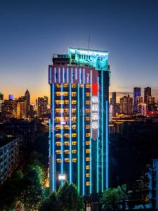 武汉ECHENG Hotel, Jianghan Road Pedestrian Street, Wuhan River Beach的一座高大的建筑,上面有五颜六色的灯光
