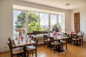 a dining room with tables and chairs and large windows at Hotel Alte Fischereischule in Eckernförde