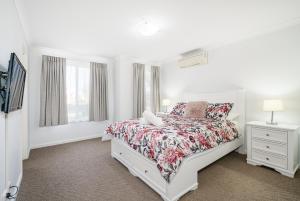 a white bedroom with a bed and a window at Ocean Blue Bungalow Easy Beach Stay in Busselton in Broadwater +5 photos