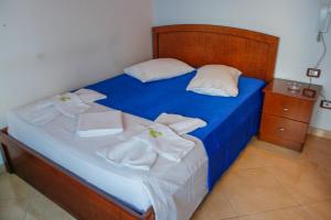Una cama con sábanas azules y toallas blancas. en Hotel Shpella, en Berat