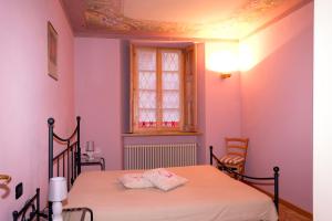 a bedroom with a bed with pink walls and a window at Casa Aurora in Cannobio