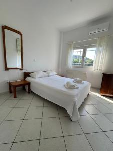 a white bedroom with a bed and a mirror at Casa Limoni in Preveza