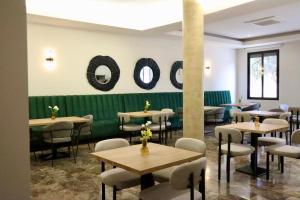 a dining room with tables and chairs and a green wall at Apartahotel Punta Calera in Los Alcázares