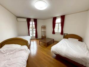a bedroom with two beds and a table in it at ホワイトホテル鎌倉 in Kamakura