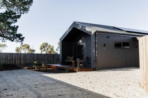 a black shed with a bench in front of a fence at Greenstone Villas - Book the entire compound! in St Helens