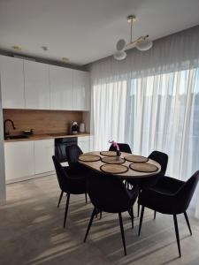 a dining room with a table and chairs and a kitchen at Baltic Essence Apartamenty 2 in Przewłoka