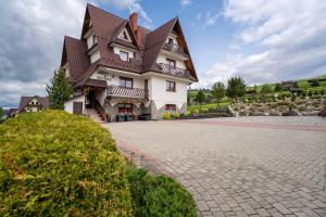 マウェ・チヘにあるApartament z widokiem na góry u Bronkaの茶色の屋根の白い大きな建物