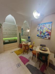 a living room with tables and chairs and a painting at Riad d'exception vue mer au coeur de la médina Essaouira - Mandji Dream in Essaouira