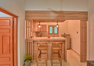 a kitchen with a counter and two chairs at a bar at Sarang Resort Varkala by VOYE HOMES - Includes Rooms with Private Pool in Varkala +53 photos