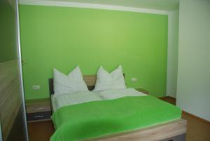 Dormitorio verde con cama con almohadas blancas en Ferienwohnung Kendler en Hüttschlag