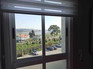 a window with a view of cars parked in a parking lot at Fonteculler centro in Culleredo