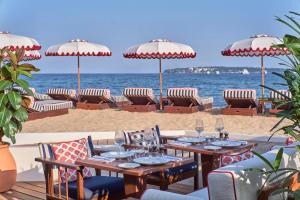 a table on the beach with chairs and umbrellas at Hôtel Barrière Le Majestic Cannes in Cannes