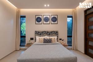 a bedroom with a large bed and two windows at StayVista at Roźe Home with Open Terrace, Pool & Pet Friendly in Calangute +32 photos
