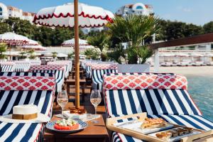 a table with chairs and plates of food on a beach at Hôtel Barrière Le Majestic Cannes in Cannes
