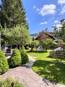 a garden with bushes and trees and a walkway at Hotel Garni Otto Huber in Oberammergau