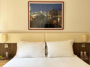 Una cama con almohadas blancas y una foto encima. en Hotel Il Moro di Venezia, en Venecia