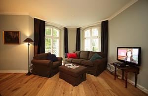 ein Wohnzimmer mit einem Sofa und einem TV in der Unterkunft Jadgschloss zu Hohen Niendorf in Hohen Niendorf