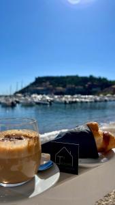 a cup of coffee and a pastry on a table next to the water at Turchetti's Rooms in Porto Ercole