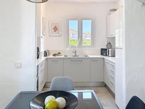 a small white kitchen with a table and a sink at Roca Fornells, Un rinconcito en el mar P107 in Fornells